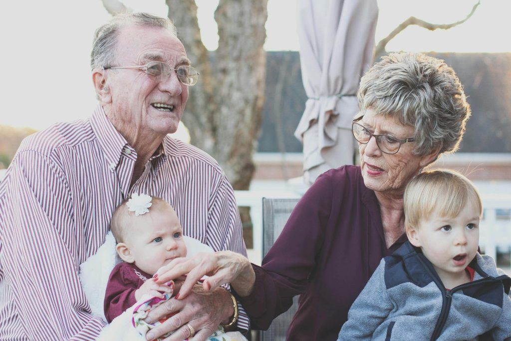 Imagen de un padre y una madre con sus dos nietos sonrientes,