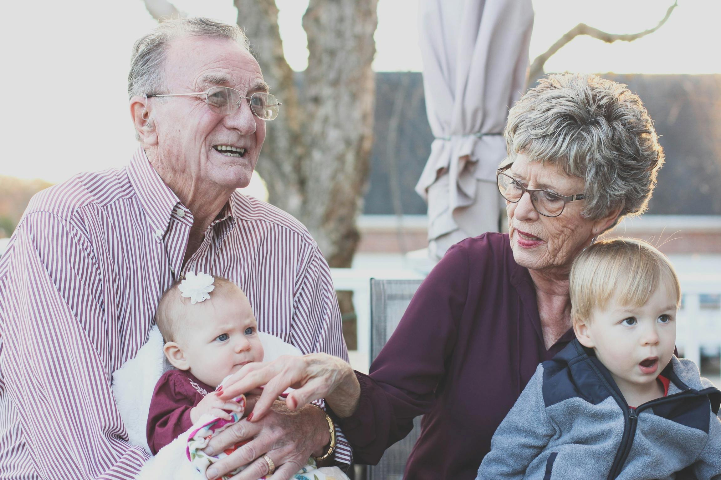 Imagen de un padre y una madre con sus dos nietos sonrientes,